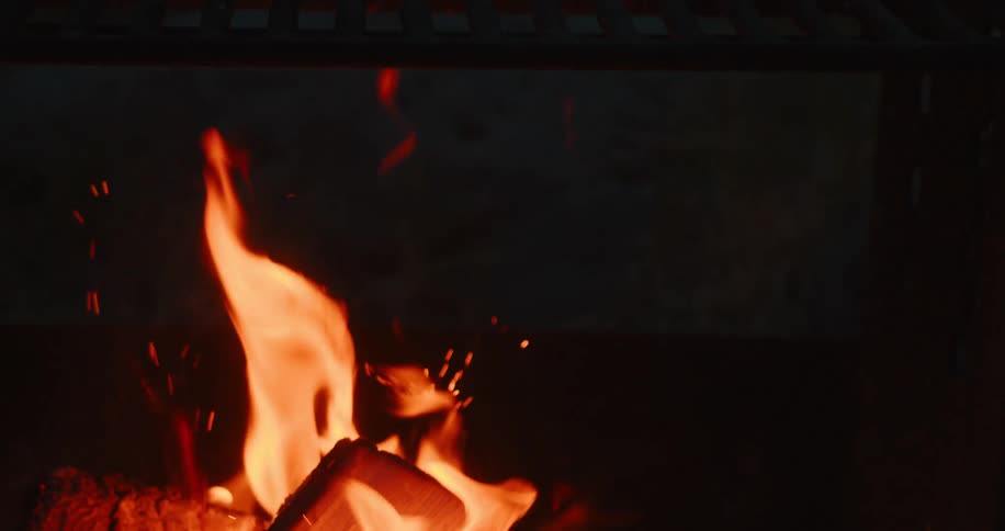 Smoke and flame come off the campfire at night
