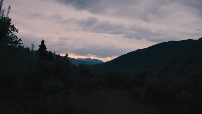 The sun is rising on a cloudy day by the mountains