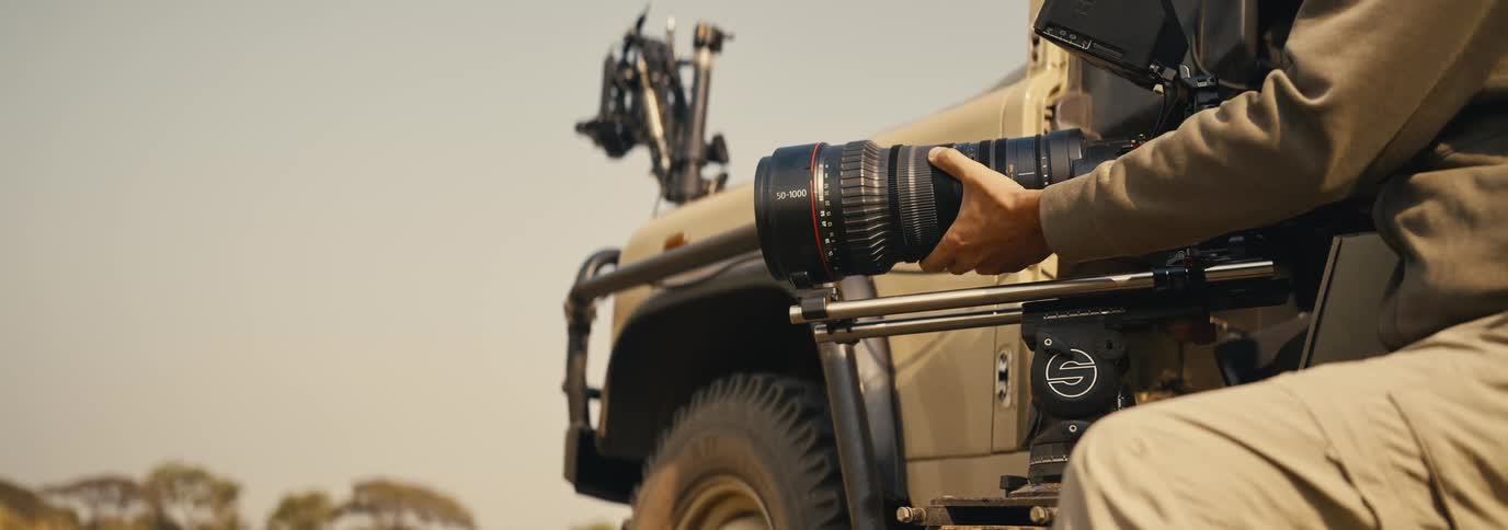The man is kneeling and taking photographs with a long lens