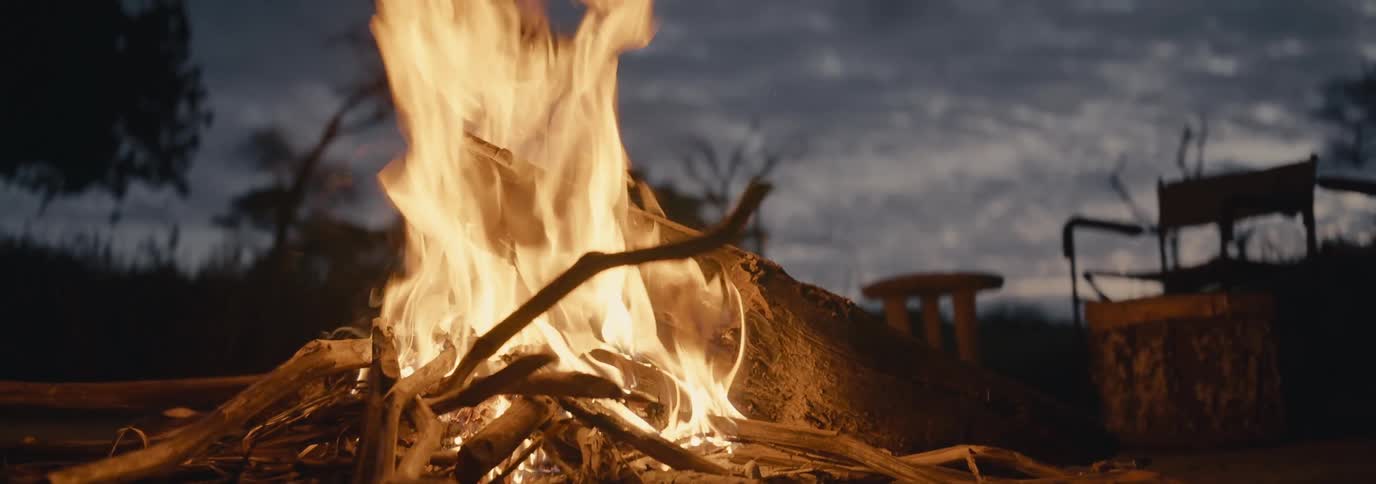 A bonfire is lit at a campsite during the night time