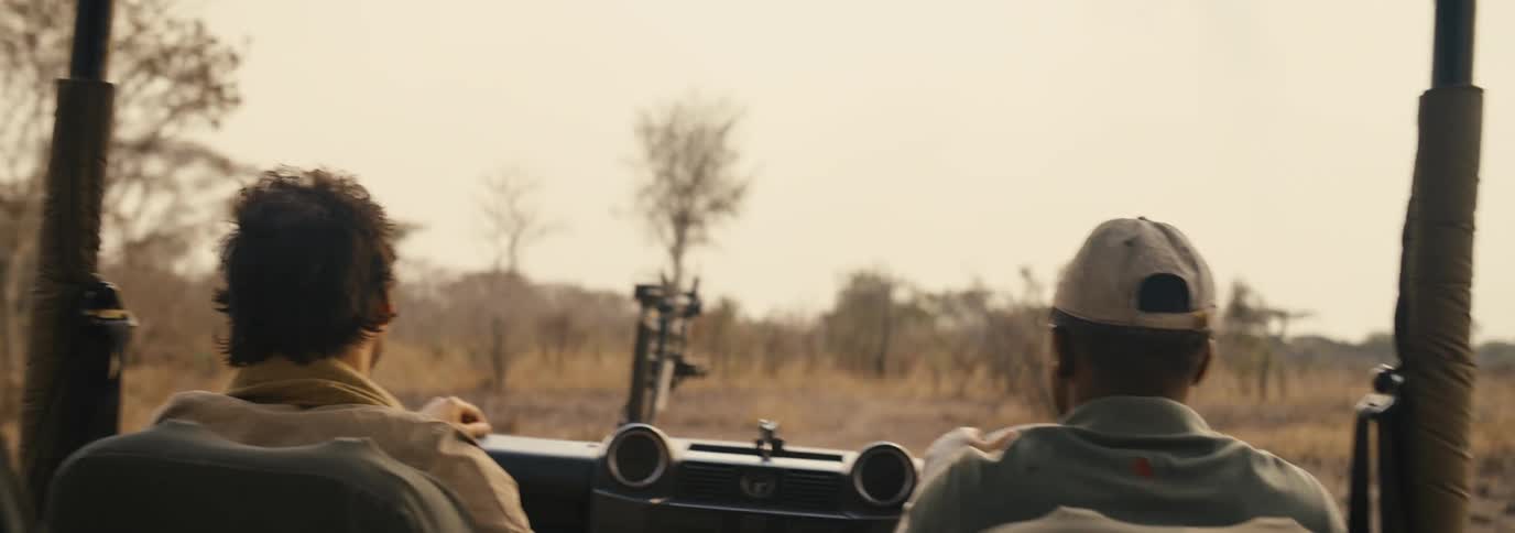 Two men ride off road in the truck through the savanna