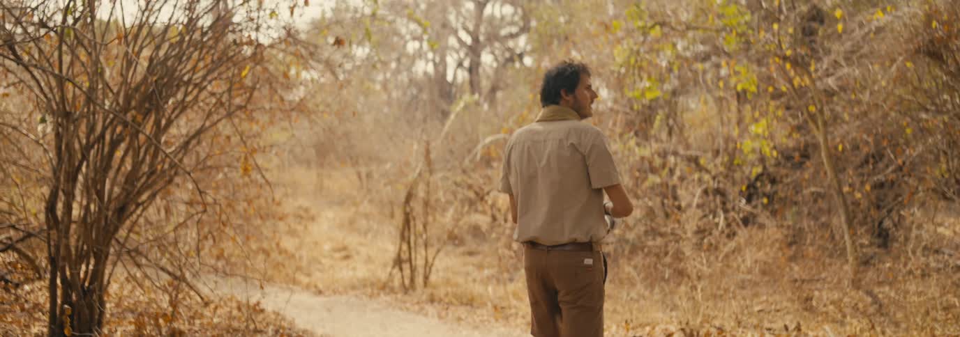 Photographer with professional camera walking in a savanna environment