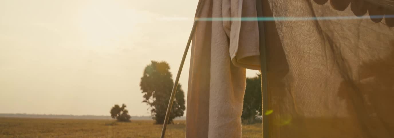 A tent stands in the wilderness at midday