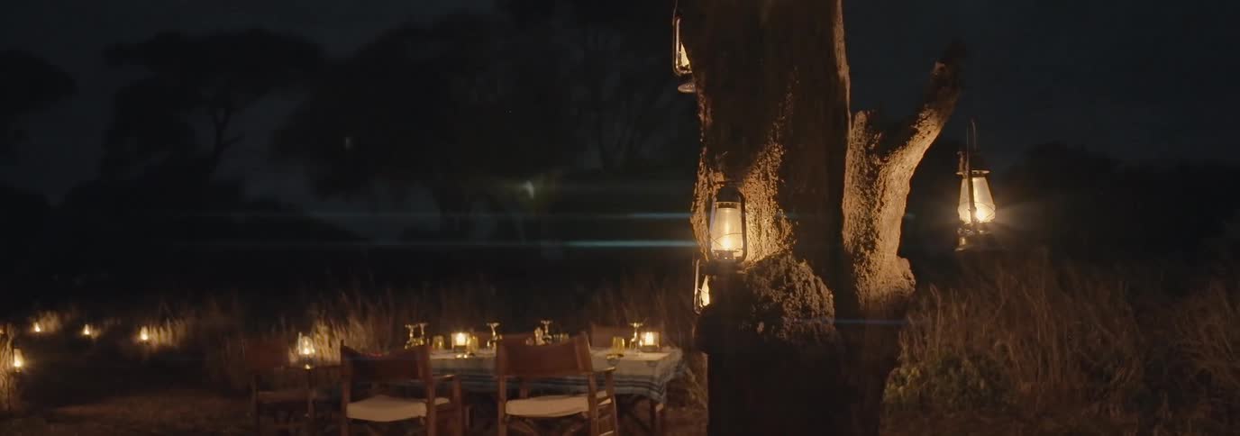 Dining tables arranged in a field at night with natural and candle lighting