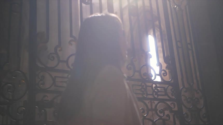 An iron gate is in front of this building as a woman walks past