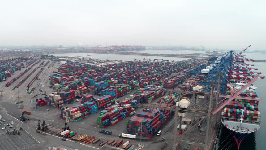 Los Angeles  seaport filled with containers and a container ship with trucks moving containers all around at midday
