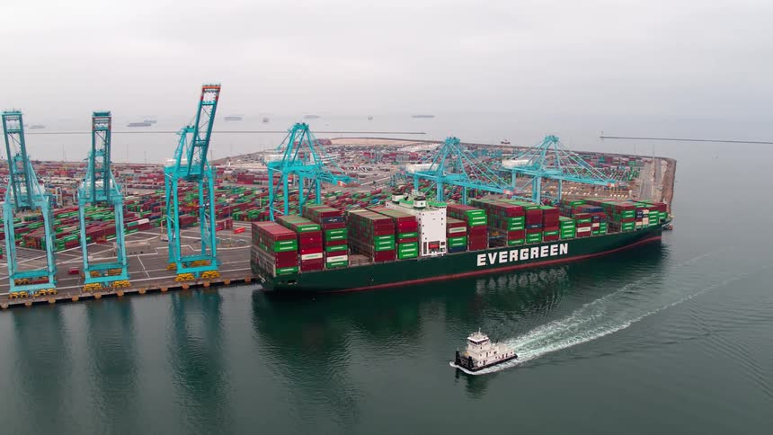 A massive container ship is being loaded and unloaded at a busy  Los Angeles  industrial port