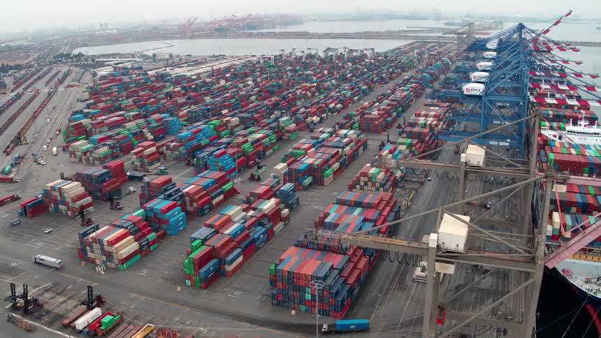 Aerial view of a large shipping port filled with colorful cargo containers and cranes near the water in Los Angeles