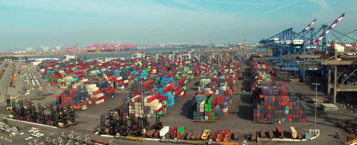 Aerial view of a busy shipping port with stacked containers and cranes in Los Angeles