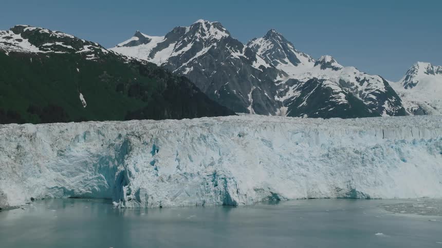 Glacier sitting in front of snowcapped mountains