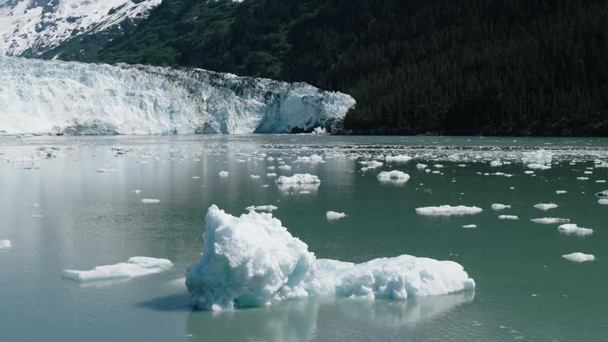 aerial view of Ice on a lake with mountains and conifers in the background in Alaska