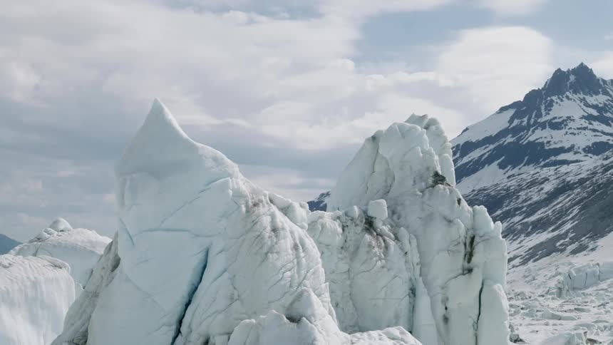 Ice mountains form in the arctic with a larger mountain covered in ice on the right side at midday