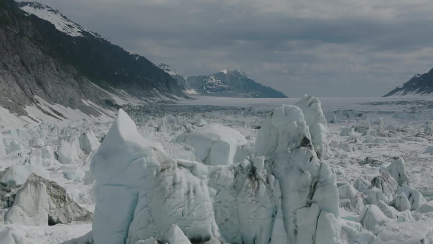 A large mass of perennial ice floats over the ocean with mountains on either side