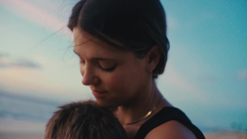 A mother kisses her son on the head at the beach