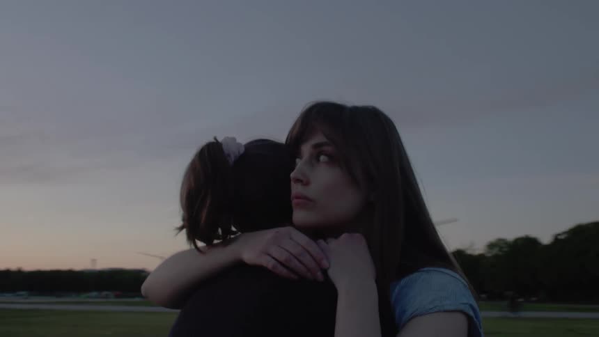 Two women hugging in a field in the late afternoon