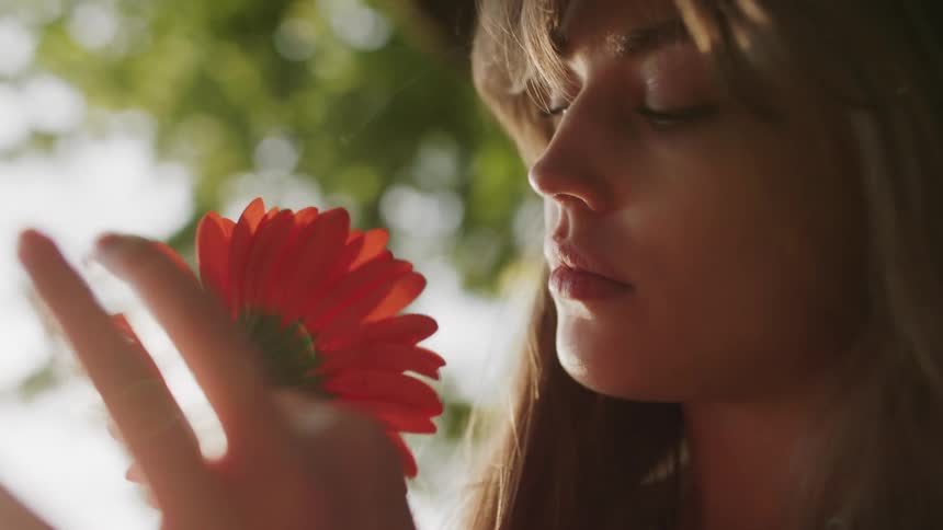 The girl turns a flower around looking at it