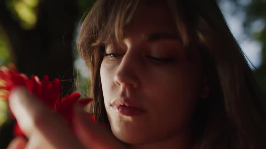 A woman is touching the red flower