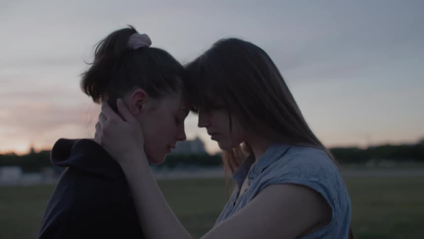 Two girls are touching heads together on the field