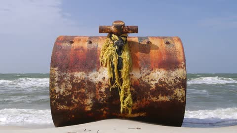 A rusty piece of metal stands on the beach
