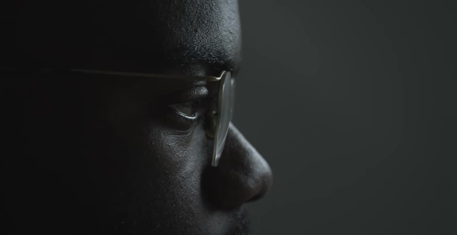 A man wearing glasses looks ahead