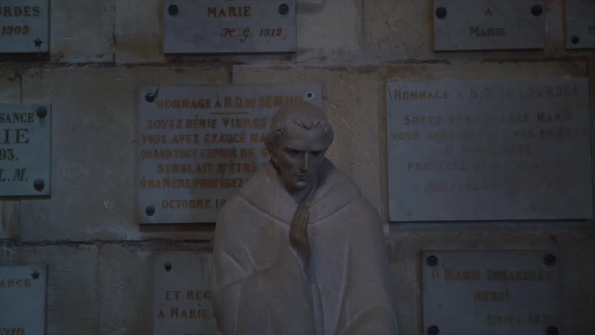 A statue next to a wall with a lot of plaques on it