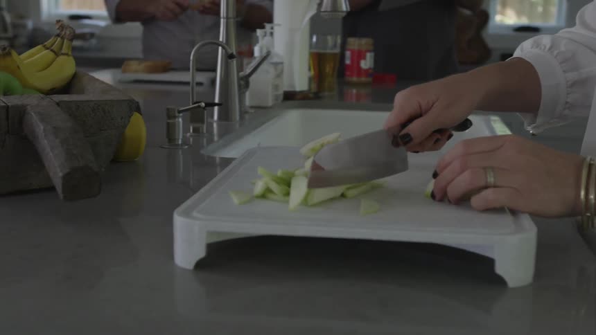 Woman chops a green apple in the kitchen