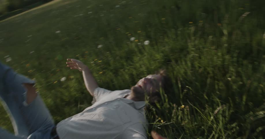 Happy man playing on grass with flowers in a field