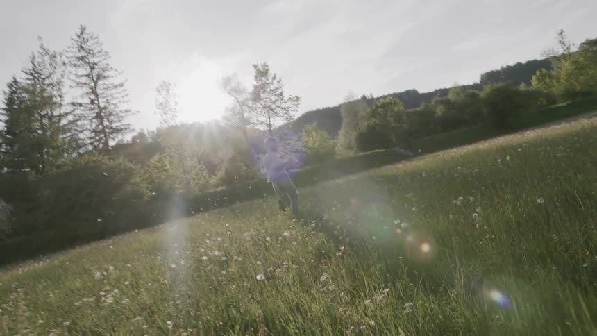 A person runs through a field towards a wooded area