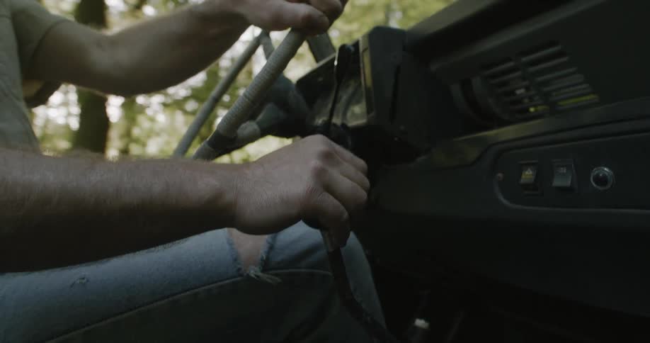 A man is driving a vehicle through a wooded town in spring