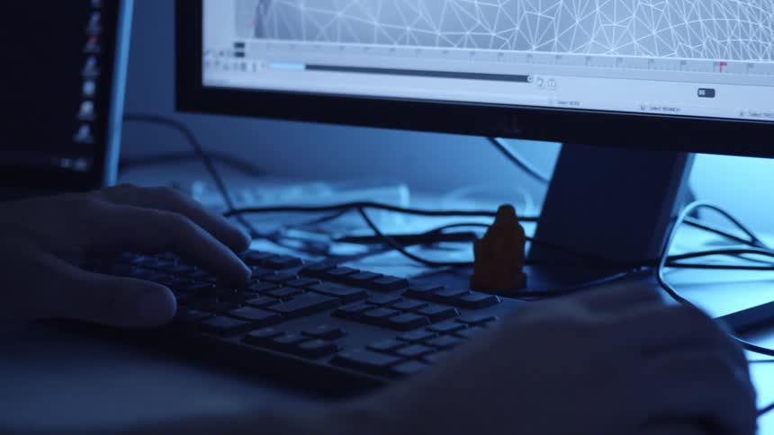 A person is working on 3d modeling or animation software at a computer workstation illuminated by blue light