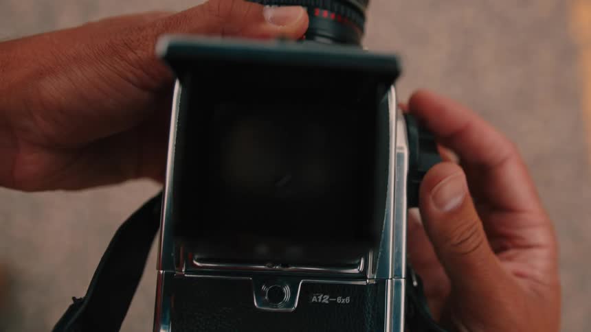 Person with two hands handling a camera
