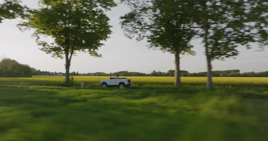 White open top jeep driving on a road across the countryside