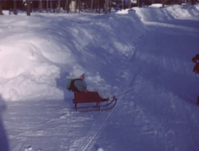 A boy drags a small sled with a baby