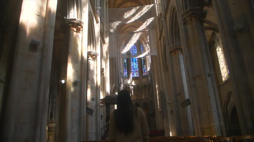 A woman gazes up at the ceiling as she walks in a cathedral