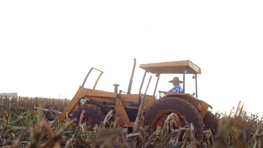An elderly man starts a farm tractor in a farm during daytime