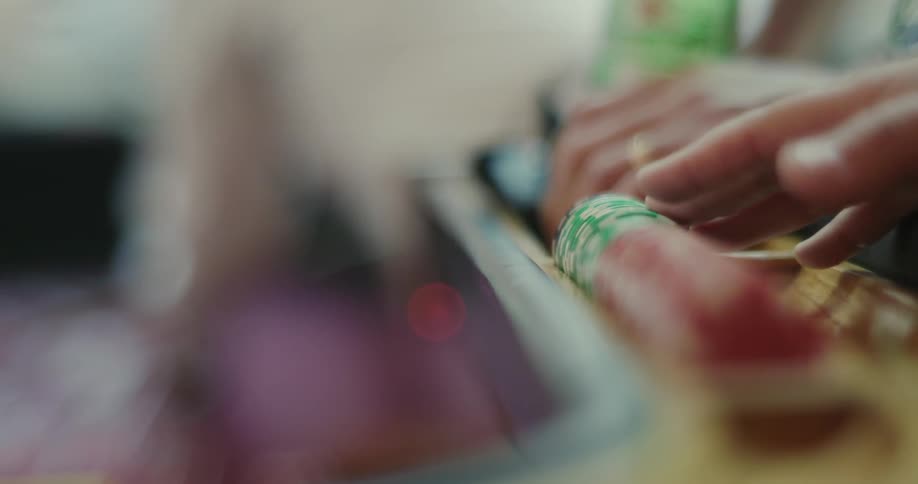 Person tapping poker chips with their fingers at a poker table