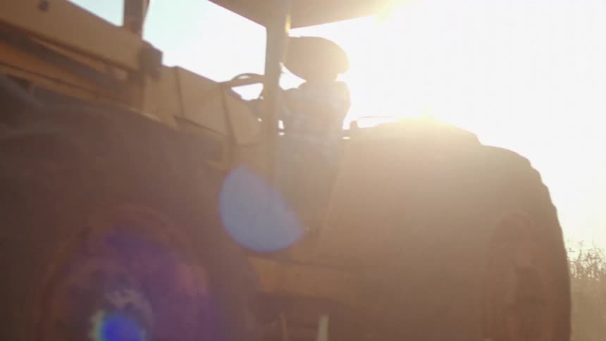 Person wearing a hat driving a tractor in an agricultural area