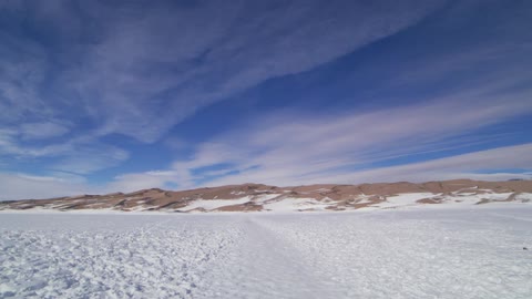 Snow covers the ground in the wilderness with mountains in the distance