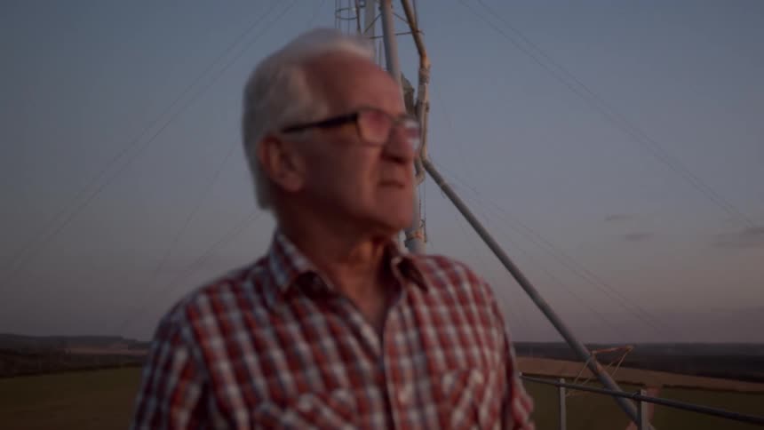 Elderly man walking on an outdoor platform at dawn