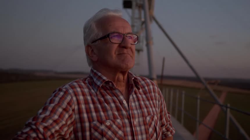 The farmer is smiling as he looks over his crops