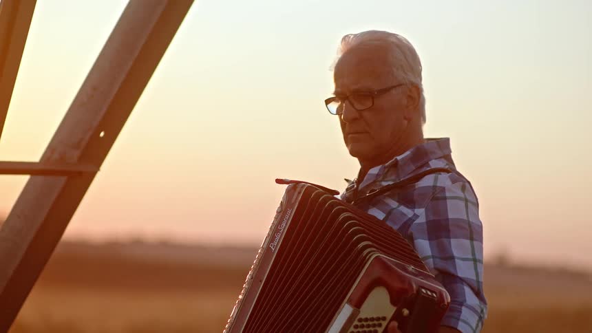 Elderly man playing harmonica outdoors