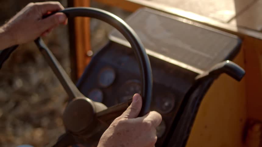 The man turns the steering wheel on the tractor