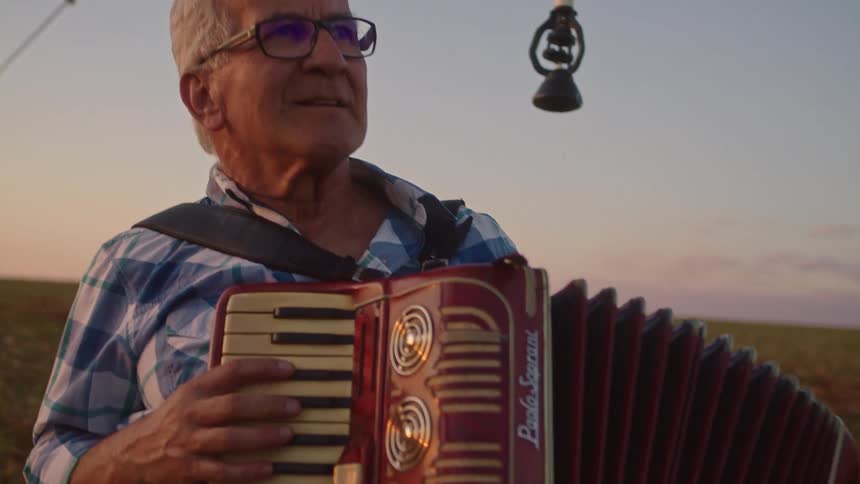 The man plays the accordion under the irrigation system