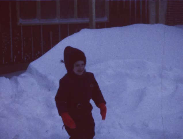 An older film of a child in a snowsuit playing in the snow