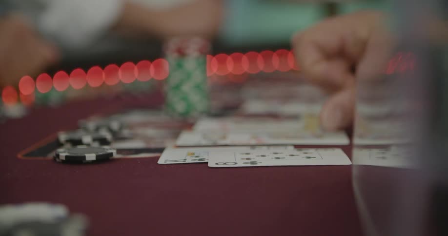 A person placing chips on the table behind some cards
