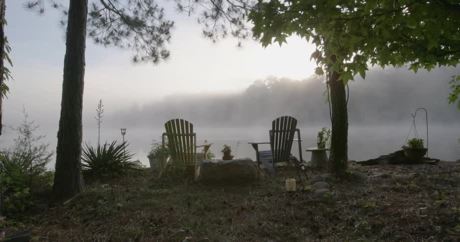 Two chairs are near the edge by a lake