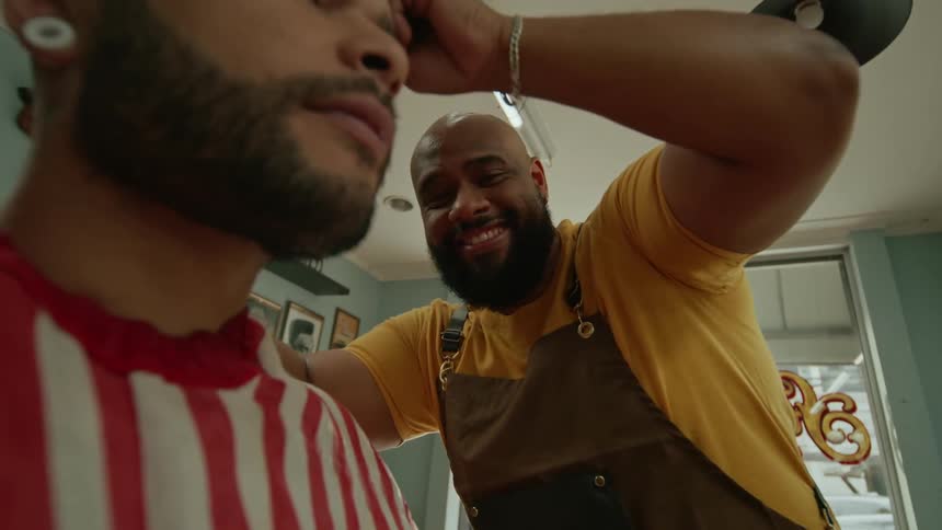 A man is sitting and receiving a haircut