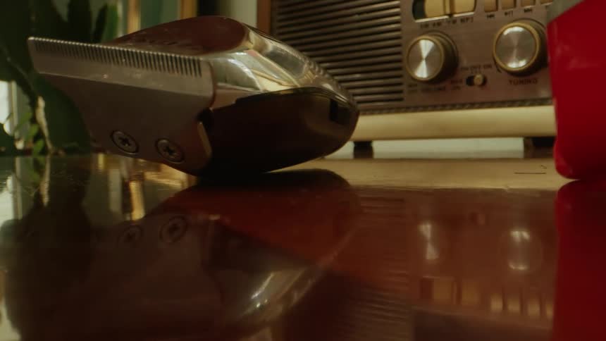 Close up of a sliver coloured hair clipper dropped on a table surface by a person in a barbing saloon during daytime