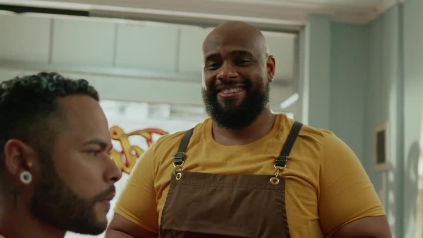 A barber begins laughing while standing by a customer