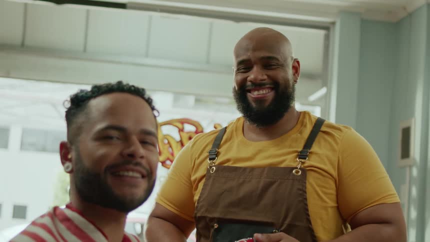 Barber and client smile warmly after a haircut in a brightly lit barbershop